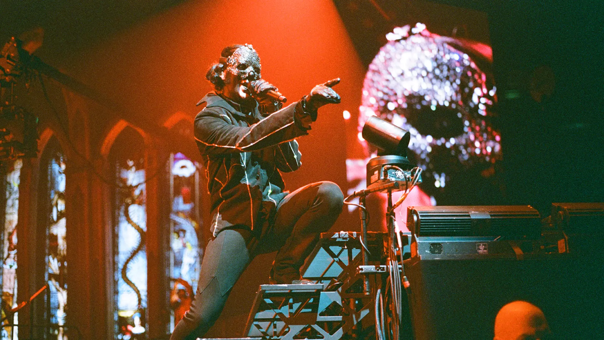 Papa IV Perpetua, the frontband of the band ghosts, is singing. A microphone is close to his face as he points to the unseen crowd in front of him.